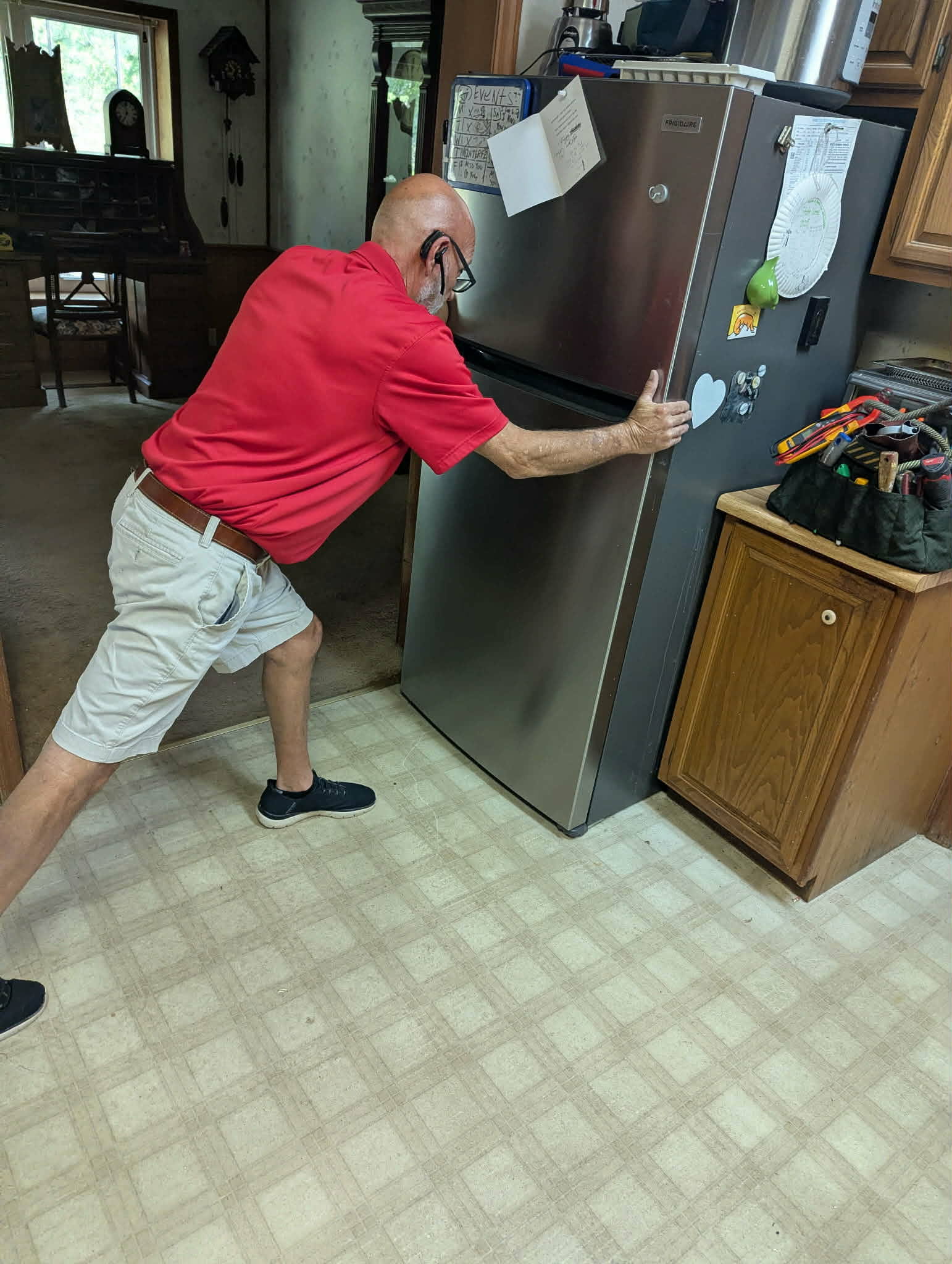 Brad Howard carefully repositioning a refrigerator during an in-home repair